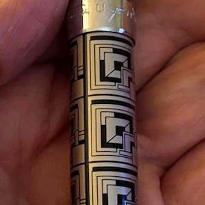 May include: A silver and black patterned pen with a rectangular design. The pen has a silver clip and a black tip. The pen is approximately 6 inches long.