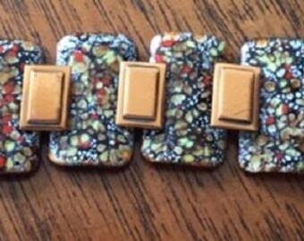 May include: A copper bracelet with a mosaic design. The bracelet is made of individual copper pieces that are joined together. Each piece has a different pattern of small, colorful pieces.