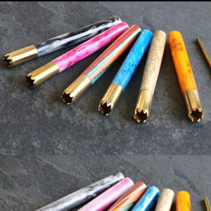 May include: A set of eight colourful smoking pipes with brass tips and a brass cleaning tool. The pipes are made from different materials, including wood, marble, and acrylic.