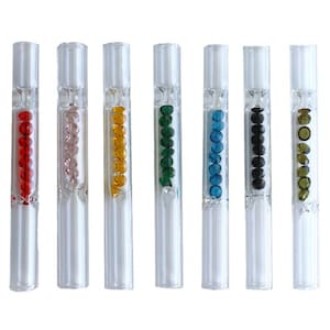 May include: Seven clear glass tubes, each filled with a different color of small, round beads. Colors include red, pink, yellow, green, blue, black, and olive green. The tubes are arranged vertically and have a cylindrical shape.