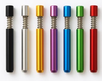 May include: An assortment of seven colorful metal pen-like tools. Each tool has a cylindrical body and a cap, with a silver spring visible in the middle. Colors include black, silver, gold, purple, blue, green, and red.