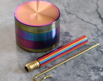 May include: A rainbow-coloured metal grinder with a matching wooden and metal poker. The grinder has a gold trim and a rainbow iridescent finish.