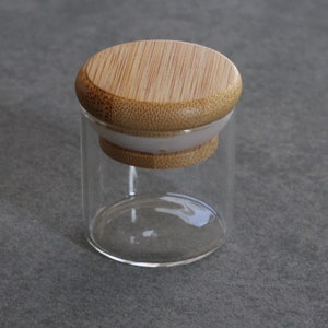 May include: A clear glass jar with a bamboo lid. The lid has a white silicone seal.
