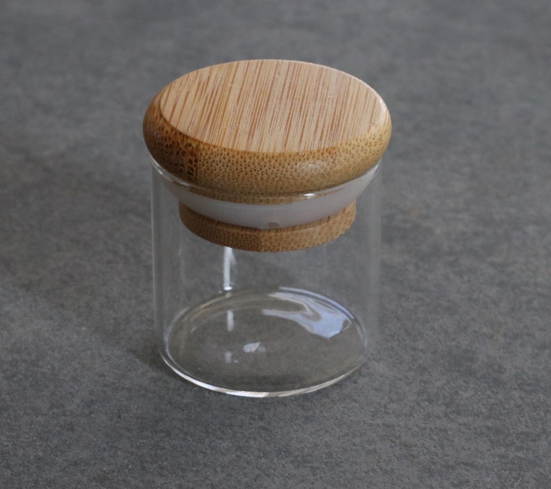 May include: A clear glass jar with a bamboo lid. The lid has a white silicone seal.