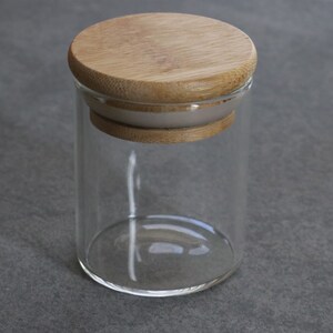 May include: A clear glass jar with a bamboo lid. The lid has a white rubber seal.