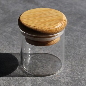 May include: A clear glass jar with a bamboo lid. The lid has a white rubber seal.