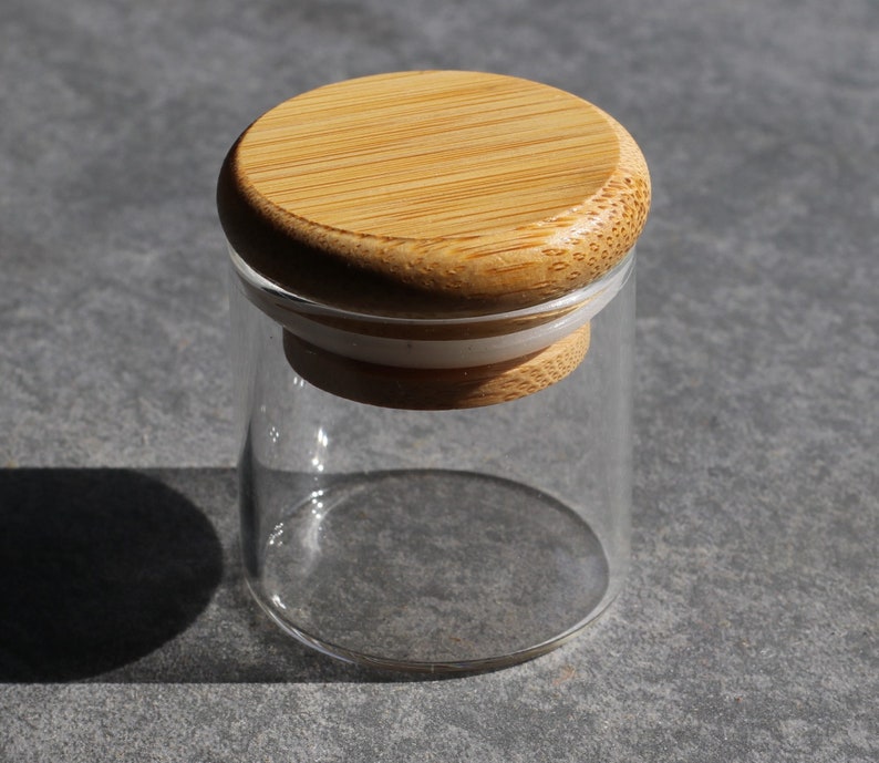 May include: A clear glass jar with a bamboo lid. The lid has a white rubber seal.