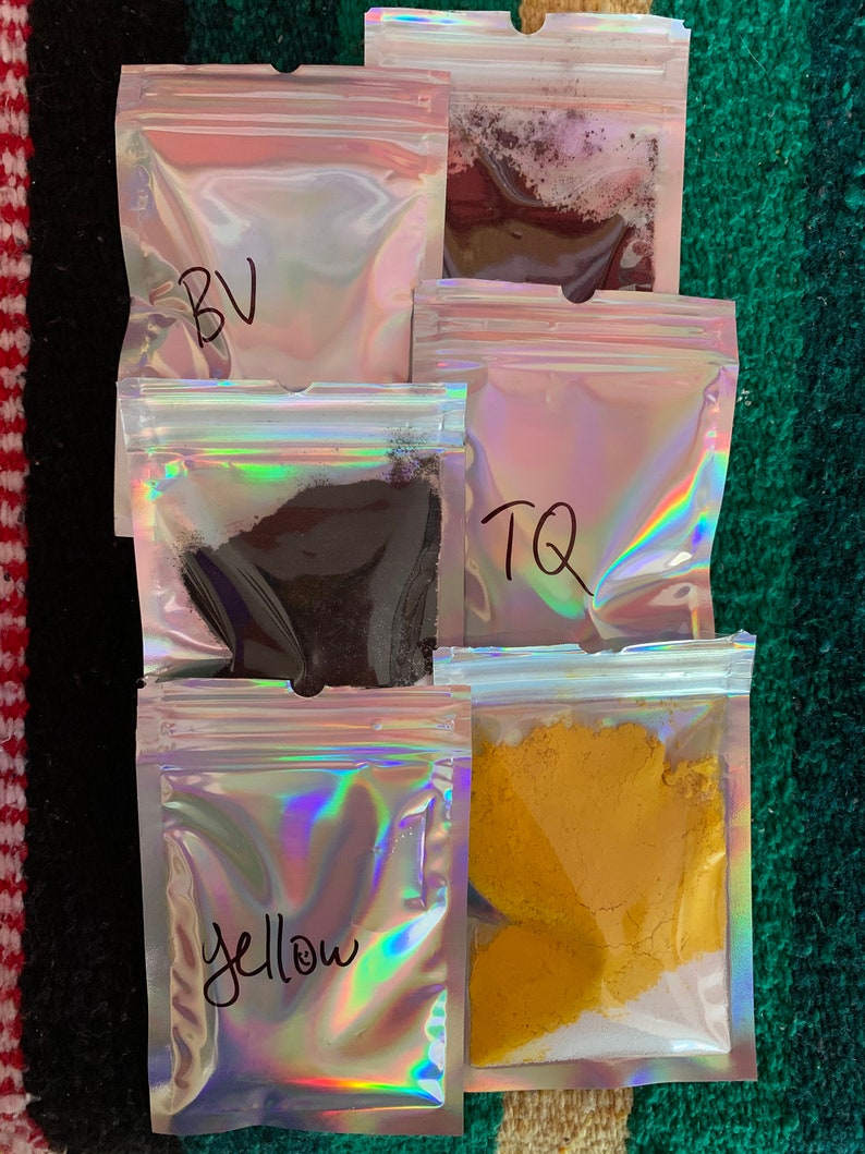May include: Five small clear plastic bags with zippers, each containing a different colored powder. The bags are labeled "BV", "TQ", "Yellow", and two are unlabeled.