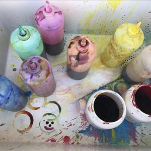 May include: A white plastic tub with eight bottles of different colored dye. The bottles have a squeeze top and are used for tie-dyeing. The tub is stained with various colors of dye.