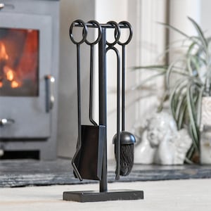 May include: Black metal fireplace tool set with a stand. The set includes a poker, shovel, tongs, and a brush.