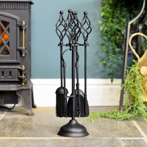 May include: A matte black fireplace tool set featuring a central stand with a circular base. The set includes a brush, a shovel, and a poker, each topped with a decorative twisted metal cage design. The tools hang vertically from the stand.