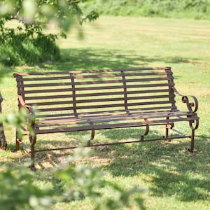 May include: A brown metal garden bench with a slatted design. The bench is sitting on a grassy lawn.
