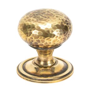 May include: A hammered brass door knob with a round, textured top and a base with a raised edge.