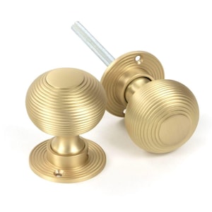 May include: A pair of gold door knobs with a ribbed design. The knobs are round and have a flat base.