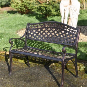 May include: A black metal garden bench with a decorative lattice design and floral accents. The bench has a curved back and scrolled armrests.