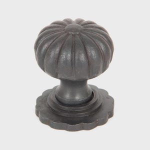 May include: A dark grey, cast iron cabinet knob with a pumpkin-shaped top and a decorative base. The knob has a textured surface and a classic design, suitable for furniture or cabinetry.