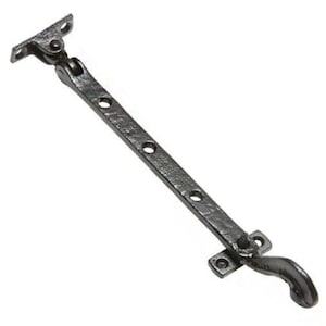 May include: Black cast iron window stay with a hook on one end and a mounting plate on the other. The stay has a textured finish and is designed to hold a window open.