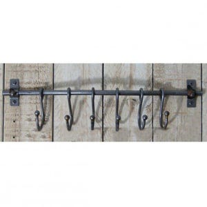 May include: A metal pot rack with six hooks. The rack is mounted to a wooden wall and is painted a dark grey colour.