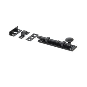 May include: Black metal door bolt with a round knob. The bolt has a rectangular base and a long, straight shaft. The knob is located at the end of the shaft. The bolt is designed to be installed on a door to secure it.