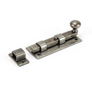 May include: A silver-toned metal door bolt with a round knob. The bolt is attached to a rectangular plate with two holes. The bolt is in the extended position.