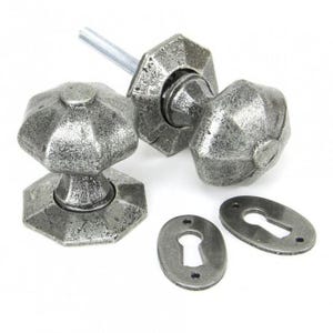 May include: A pair of antique silver door knobs with a faceted design and matching keyhole escutcheons.