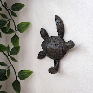 May include: A cast iron turtle wall hook in a dark brown finish. The turtle is facing to the right and has a hook on its tail.