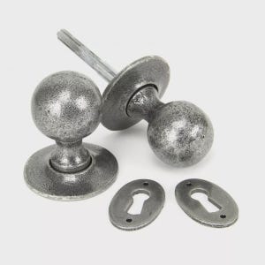 May include: A set of antique-style door hardware, featuring two spherical doorknobs, a connecting bolt, and two keyhole covers. The hardware has a distressed, silver finish, giving a vintage look. Suitable for home renovation projects.