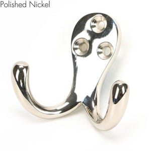 May include: A polished nickel double hook with three screw holes. The hook is designed with a curved shape and a smooth finish.