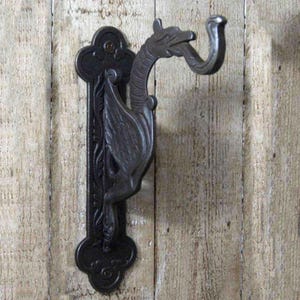 May include: Black cast iron wall mounted hook with a dragon design. The hook is attached to a decorative plate with intricate details.
