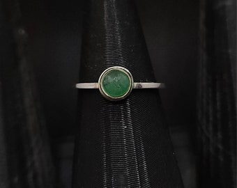 May include: A silver ring with a green oval gemstone set in a bezel setting.