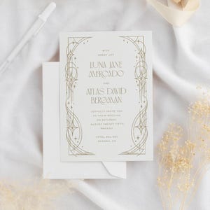May include: A wedding invitation with a gold art deco design. The invitation includes the names Luna Jane Mercado and Atlas David Bergman, along with the wedding date and location. The invitation is on a white background with a white envelope.