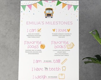 May include: A white milestone poster for Emilia featuring a yellow school bus graphic, colorful bunting, and pink text. It lists milestones including I can, I love, favorite foods, favorite books, 31 inches tall, 14 teeth, and 30 pounds.