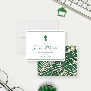 May include: A white and green moving announcement card with the text "WE HAVE Just Moved". The card features a key graphic and is accompanied by an envelope and a patterned card with green leaves.