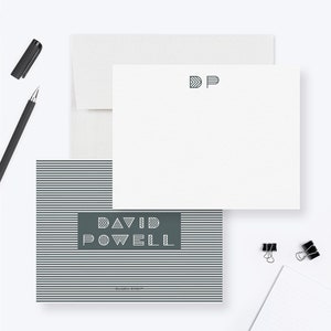 May include: A set of grey and white striped stationery with a dark grey rectangle featuring the text "DAVID POWELL" in a geometric font. The matching envelope has the initials "DP" in the same geometric font.