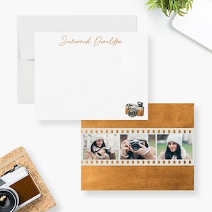 May include: A set of three personalized stationery cards with a gold foil background and a film strip design. The cards feature a watercolor illustration of a vintage camera and three photos of a person holding a camera. The name "Savannah Donaldson" is written in gold foil on the top card.