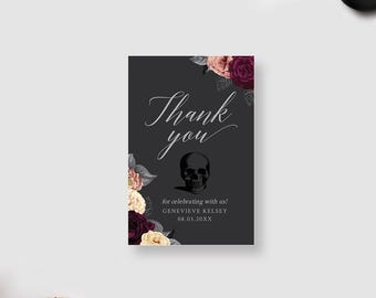 May include: A rectangular thank you card on a dark gray background featuring a central human skull illustration, floral accents in shades of burgundy and cream, and the text Thank you for celebrating with us! GENEVIEVE KELSEY 08.03.20XX.