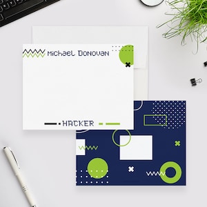 May include: A white card with a green and black geometric design and the text "Michael Donovan" and "Hacker". The card is on top of a blue card with a green and white geometric design.