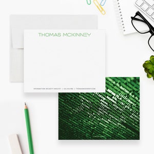 May include: A white card with green text that reads "THOMAS MCKINNEY" at the top. Below the name is the text "INFORMATION SECURITY ANALYST | 555.256.986 | THOMASMCKINNEY.COM". The card is partially obscured by a green and black image of computer code.