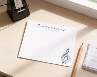 May include: A square white notepad featuring the text "Just a note from" followed by "MRS. SANDERSON" in black ink. The design includes a small musical note icon at the top and a large blue treble clef graphic in the bottom right corner.