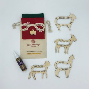 May include: A craft kit for making felt animal ornaments. The kit includes four wooden animal shapes: a sheep, a goat, a llama, and a lamb. The kit also includes felt, yarn, a needle, a comb, and glue. The kit is packaged in a drawstring bag with the Casa Marengo Collection logo.