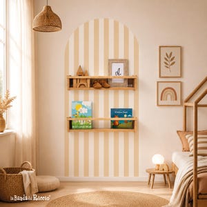 Peut inclure: Une chambre d'enfant chaleureuse avec des étagères en bois clair présentant des livres, des jouets et des cadres. Le mur est orné de rayures crème et beige. Un panier en osier, un tapis rond et un lit en bois complètent l'ambiance.