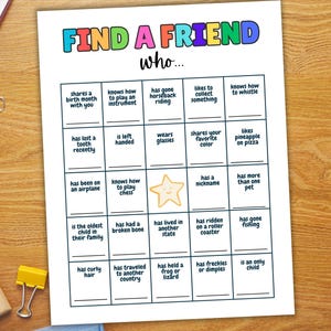 May include: A white paper with the text "FIND A FRIEND" in colorful letters. The game sheet has boxes with prompts like "shares a birth month with you" and "likes pineapple on pizza".