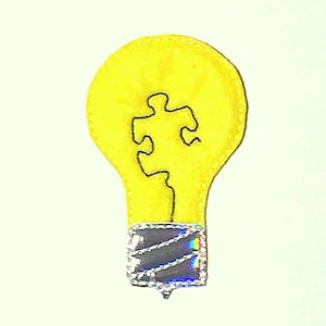 May include: A yellow lightbulb with a black puzzle piece inside. The lightbulb has a silver base.