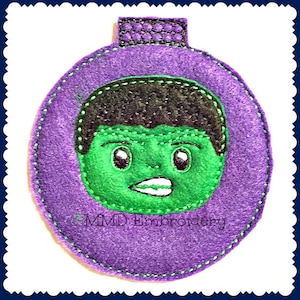 May include: Purple felt ornament with a green embroidered face of the Hulk, with the text "MMD Embroidery" at the bottom.