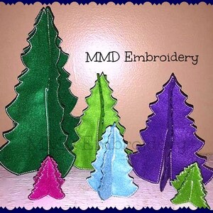 May include: A set of six felt Christmas trees in various sizes and colors, including green, purple, blue, and pink. The trees are arranged in a row, with the largest tree in the back and the smallest tree in the front. The trees are all decorated with white stitching. The text "MMD Embroidery" is visible at the top of the image.