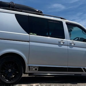 Puede incluir: Una furgoneta plateada con ruedas negras y un portaequipajes de techo negro. La furgoneta tiene una franja negra a lo largo del lateral con el texto "Edition 30" en ella.