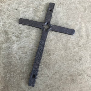 K&ouml;nnte beinhalten: Ein dunkelgraues Metallkreuz mit einem dekorativen Design in der Mitte. Das Kreuz ist aus dickem Metall gefertigt und hat einen rustikalen Look.