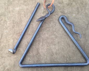Puede incluir: Un hogar triangular de metal con un diseño de serpiente en un lado y un atizador con un gancho en el extremo.