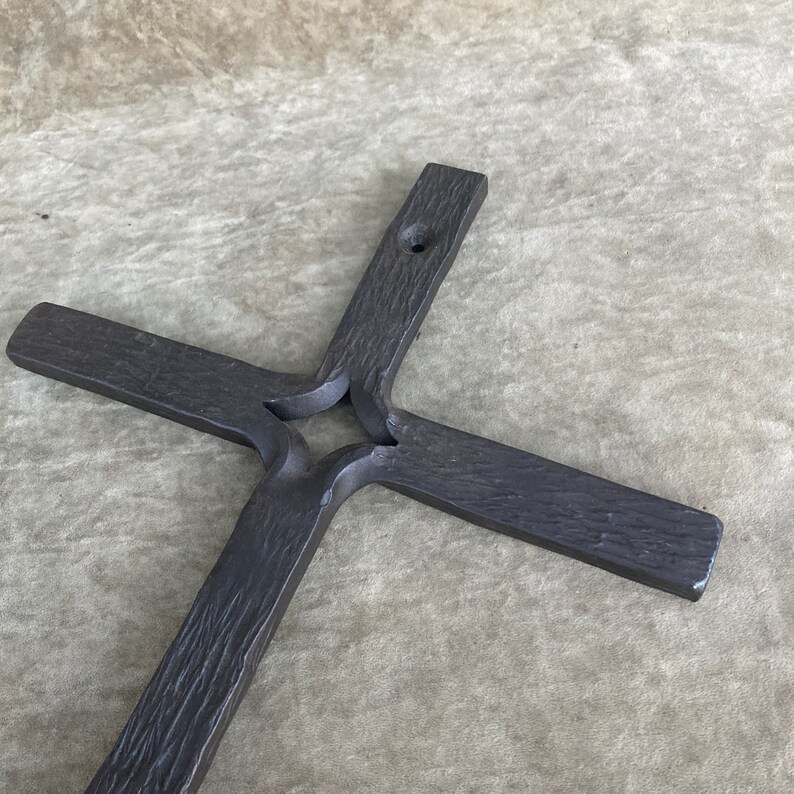 K&ouml;nnte beinhalten: Ein schwarzes Metallkreuz mit einem sternf&ouml;rmigen Ausschnitt in der Mitte. Das Kreuz ist aus dickem, strukturiertem Metall gefertigt und hat ein rustikales Aussehen.
