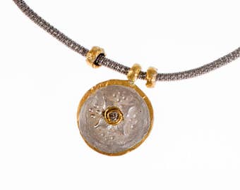 May include: A silver and gold necklace with a round pendant featuring a floral design and a small diamond in the center.